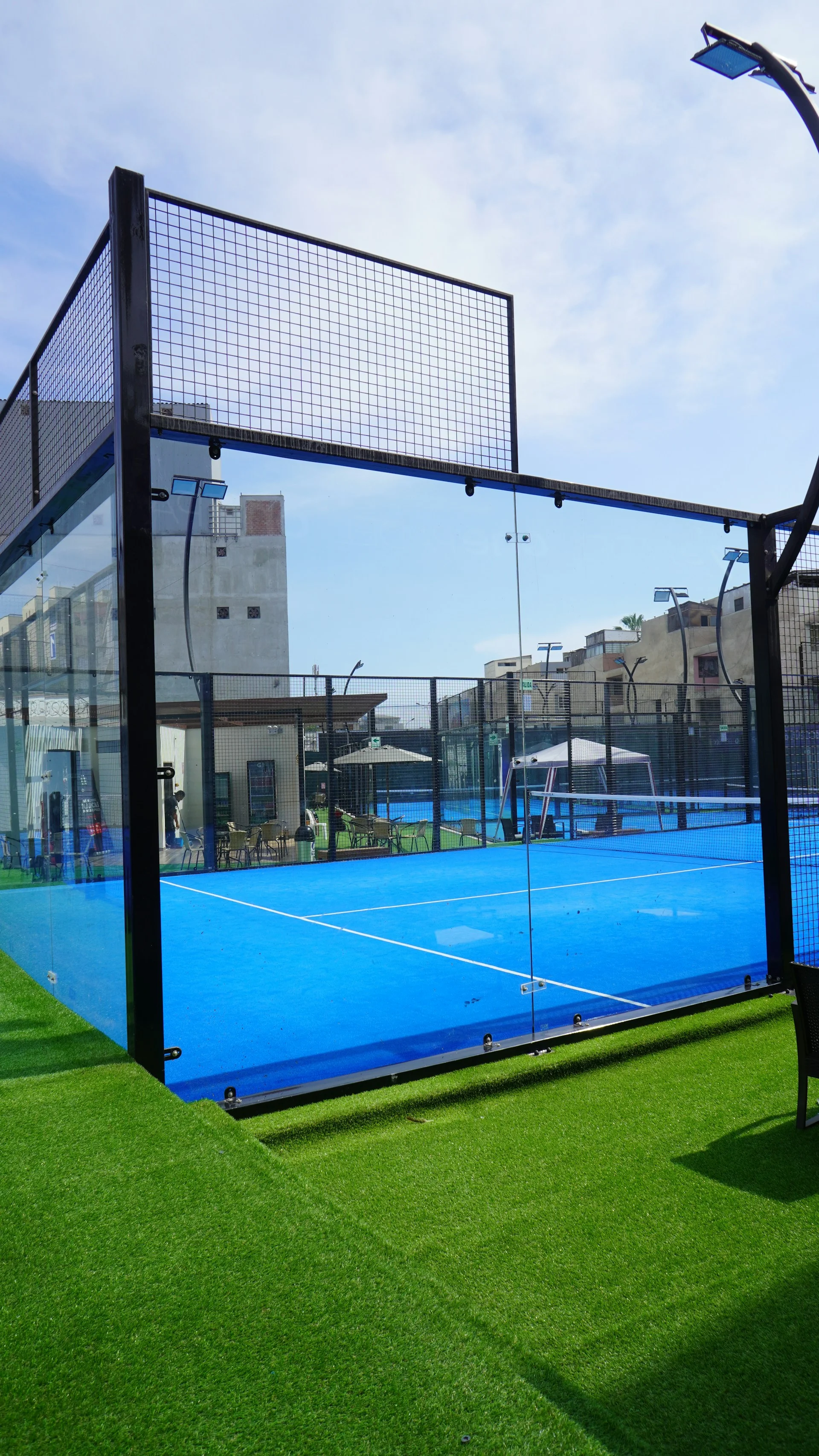 Padel court with net and glass walls — interior view