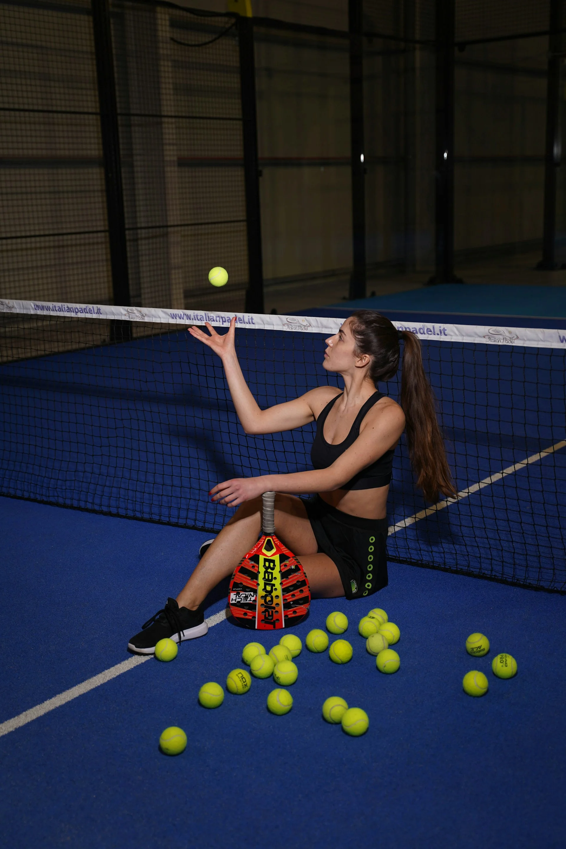 Jogador iniciante de padel com raquete e bolas no campo