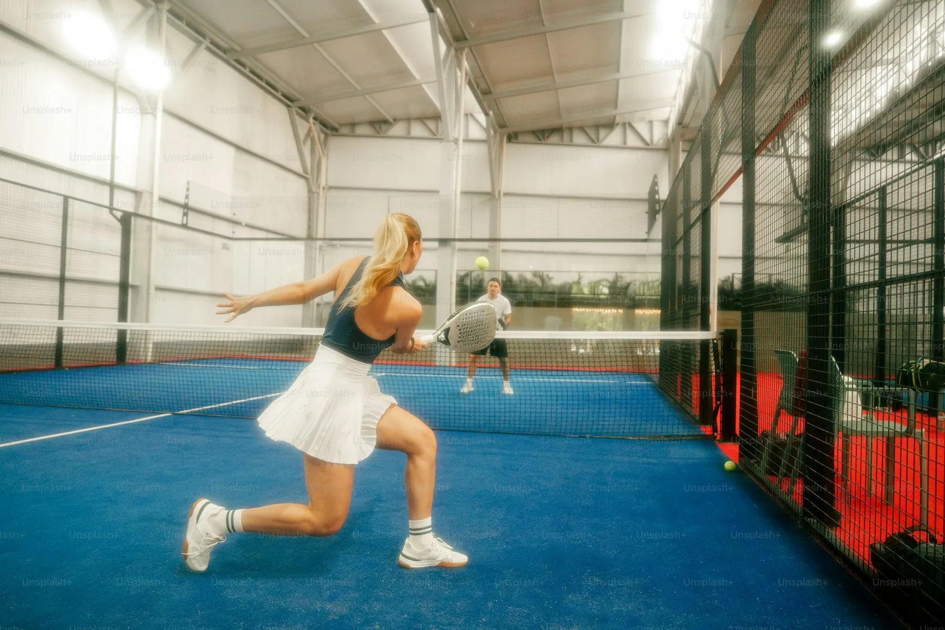 Two padel players on different court sides